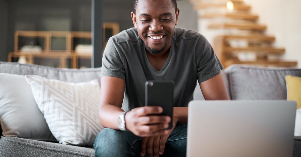 A man sits in his living room, reading the latest crypto news on his phone.