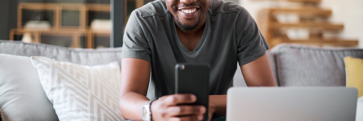 A man sits in his living room, reading the latest crypto news on his phone.