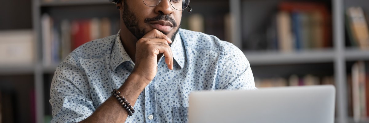 A man sits at his desk and reads the latest news off his computer.
