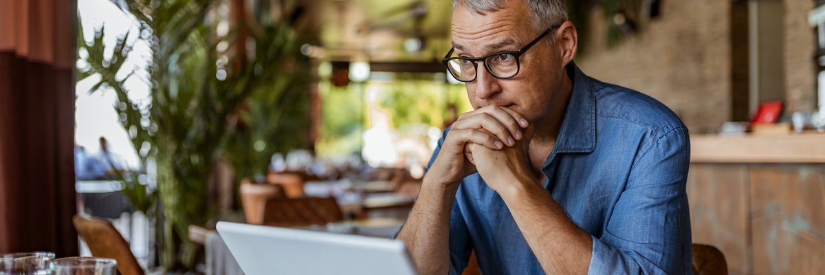 Man sits at laptop and appears to be in thought.