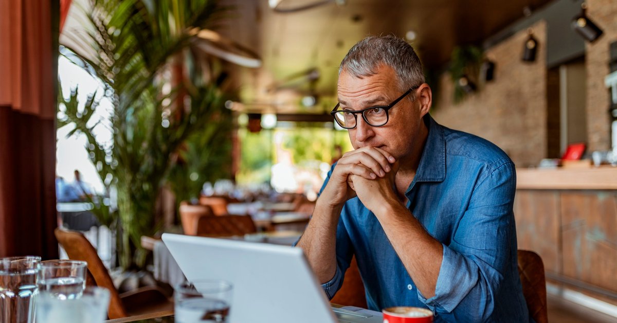 Man sits at laptop and appears to be in thought.