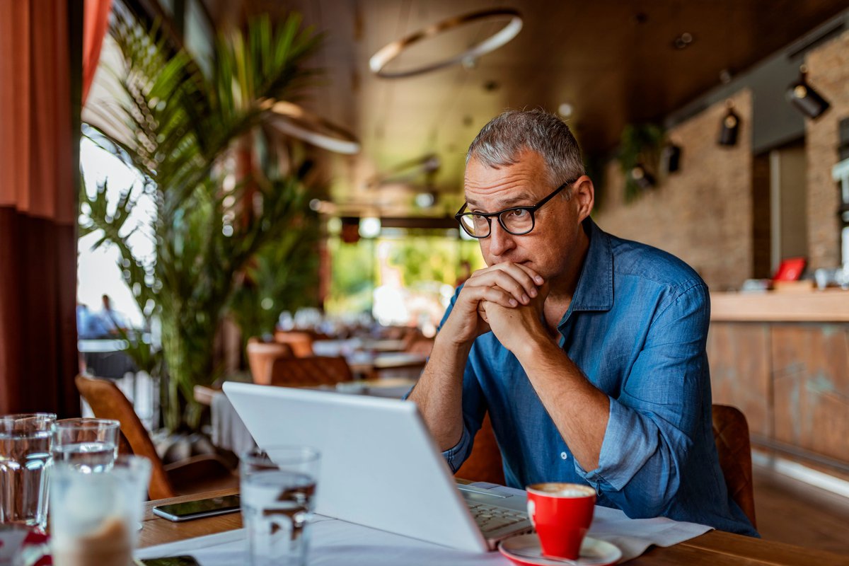 Man sits at laptop and appears to be in thought.