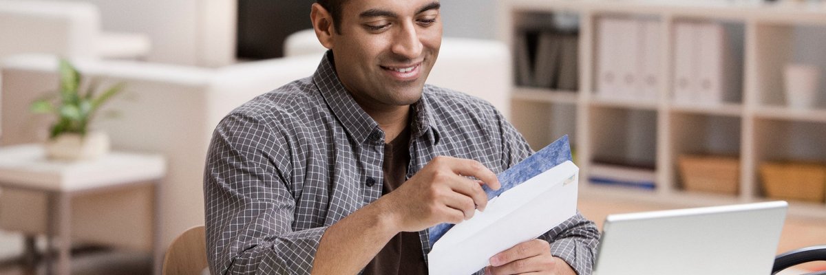 Man smiling at the contents of an open envelope.