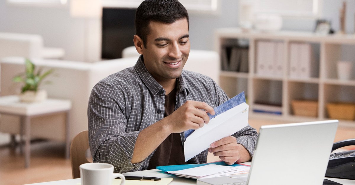 Man smiling at the contents of an open envelope.