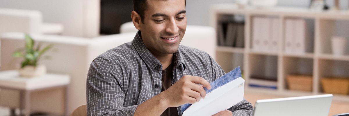 Man smiling at the contents of an open envelope.