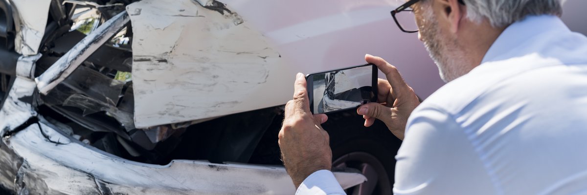 Man taking photos of damage to a vehicle.