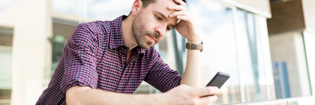 A man looking upset while reading something on his phone.
