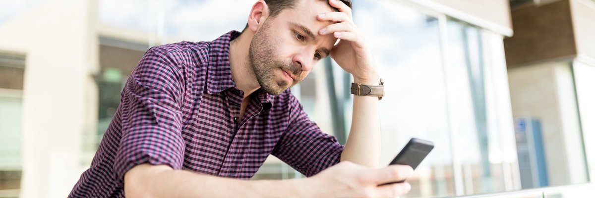 A man looking upset while reading something on his phone.
