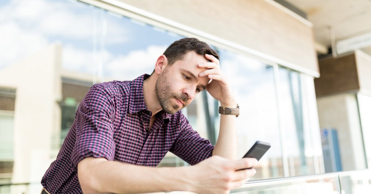 A man looking upset while reading something on his phone.