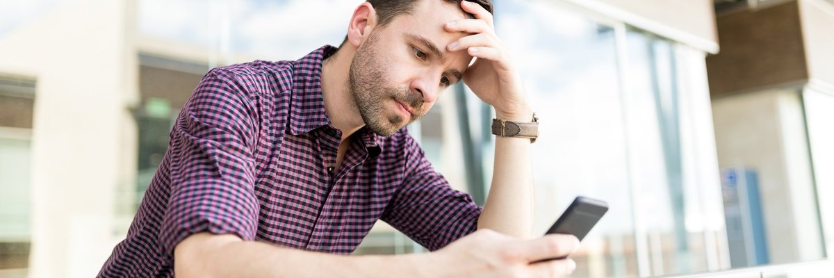 A man looking upset while reading something on his phone.
