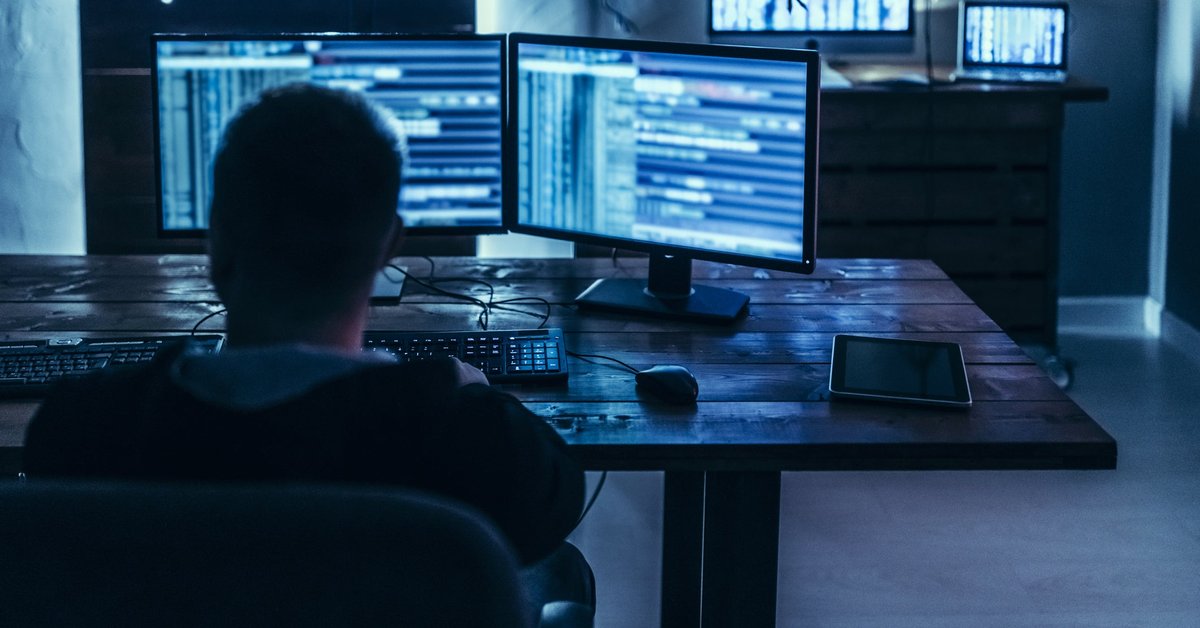 Man using high-tech computer system in dimly lit room.