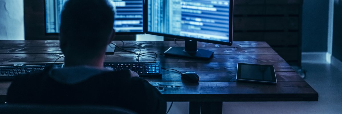 Man using high-tech computer system in dimly lit room.