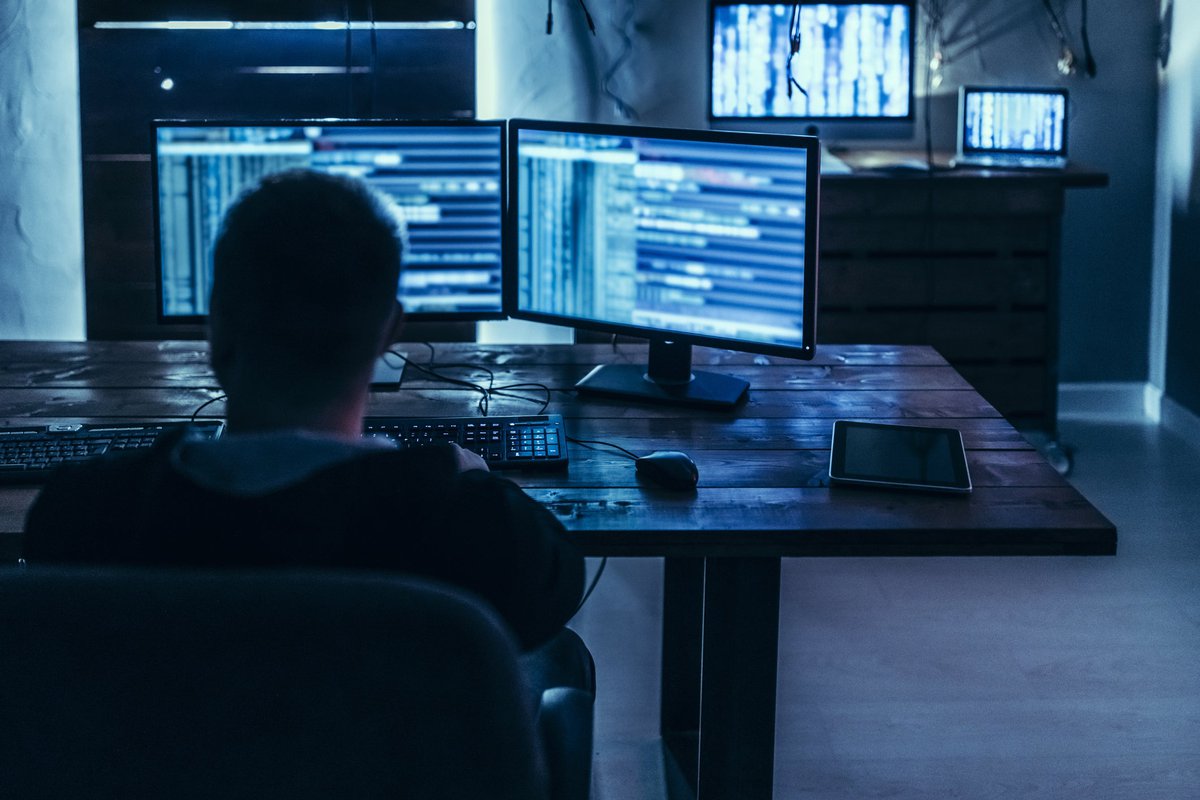 Man using high-tech computer system in dimly lit room.