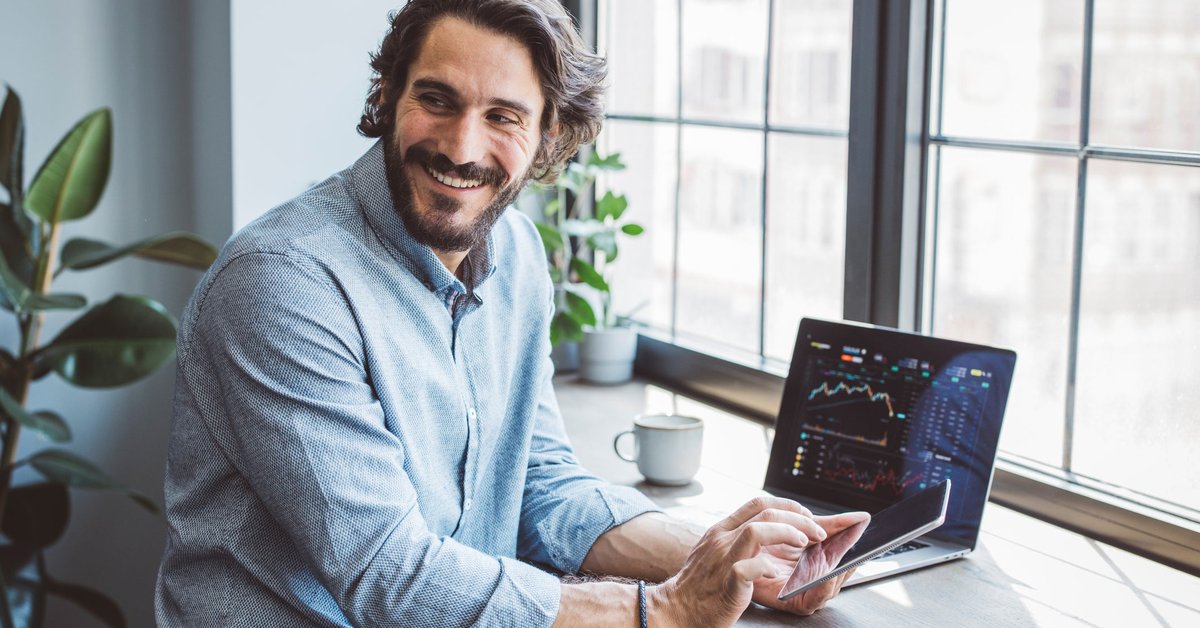 Man using laptop and cell phone to look at data.