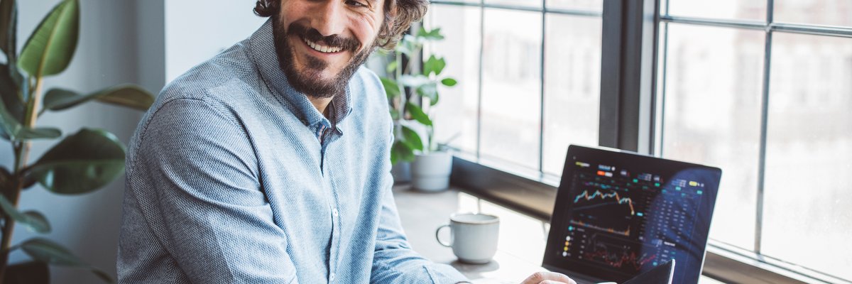 Man using laptop and cell phone to look at data.