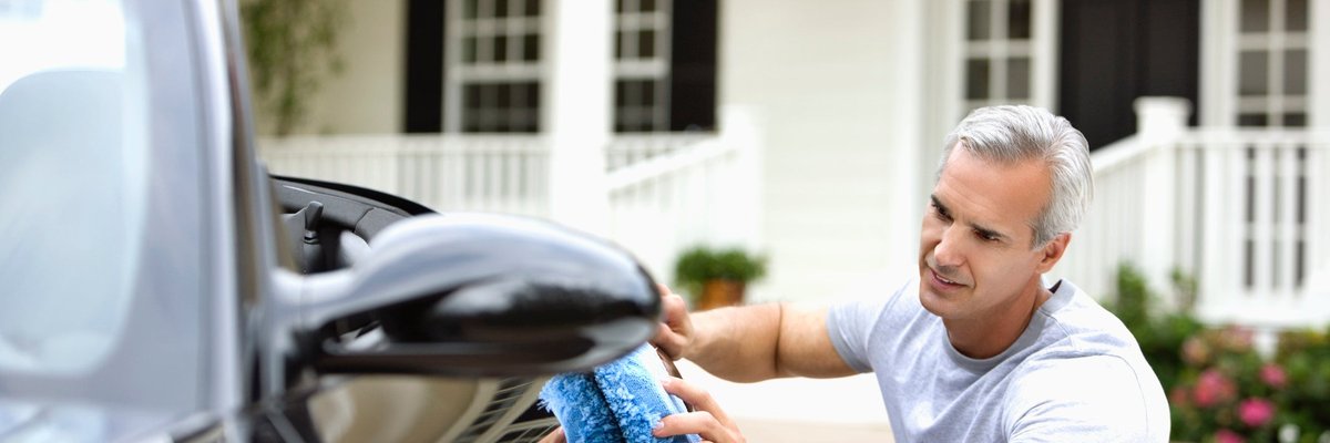 Man waxing his car in front of house.