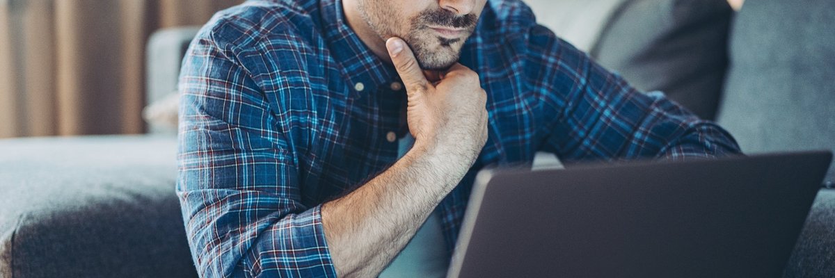 Man with glasses looking at laptop.