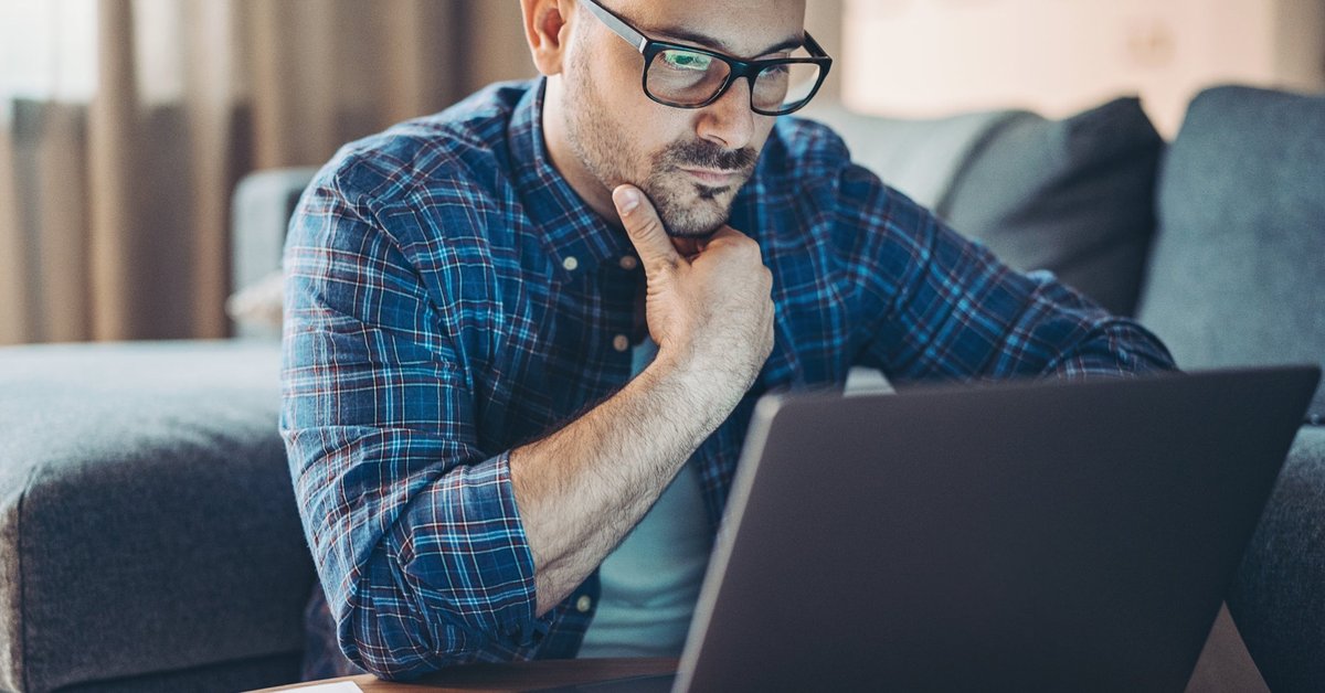 Man with glasses looking at laptop.