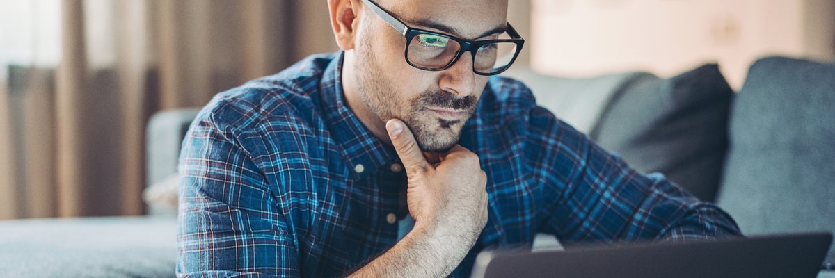 Man with glasses looking at laptop.