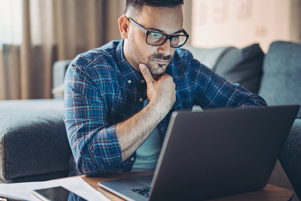 Man with glasses looking at laptop.