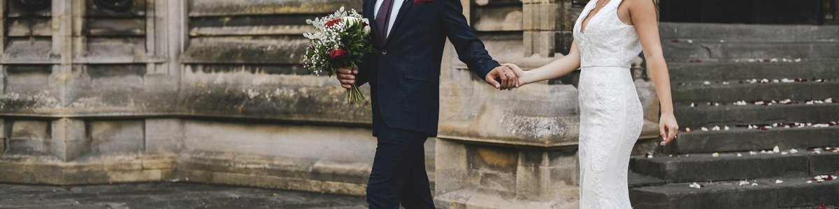 A married couple walking out of church holding hands and looking at each other.