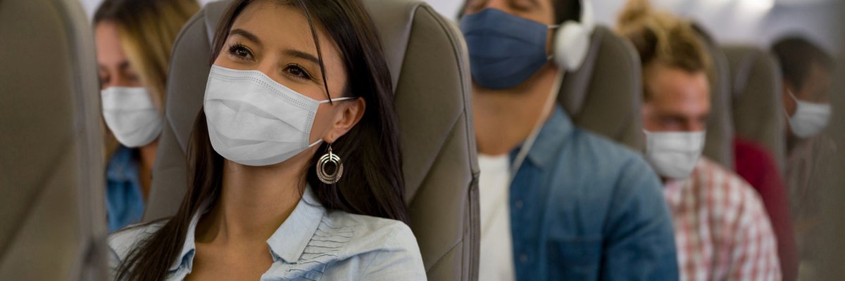A row of masked passengers on an airplane.