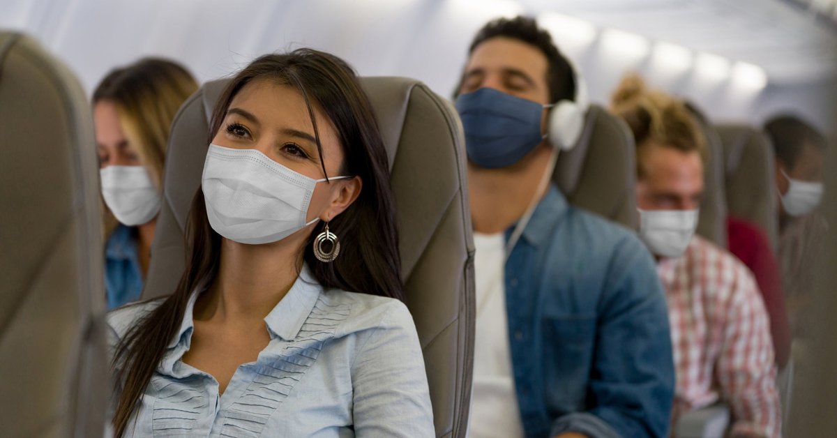 A row of masked passengers on an airplane.