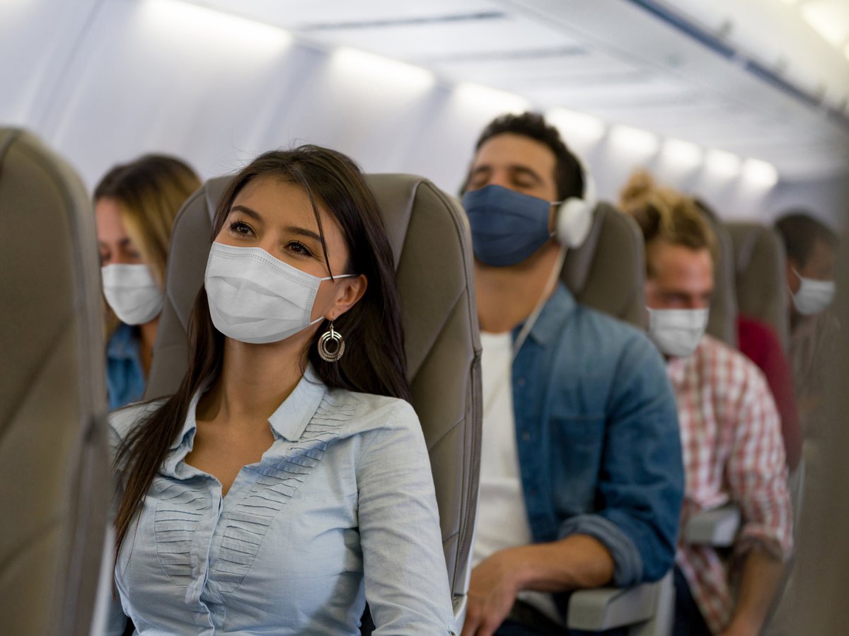 A row of masked passengers on an airplane.