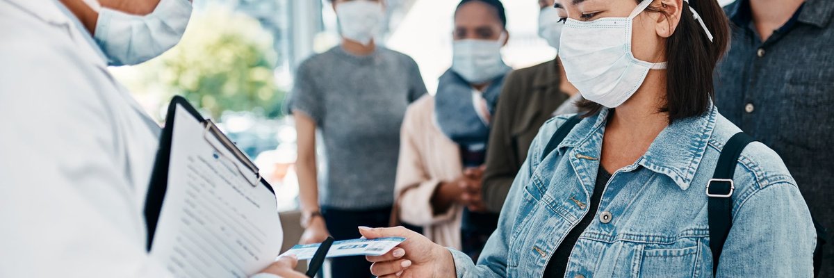 Masked travelers going through airport customs check with passports.
