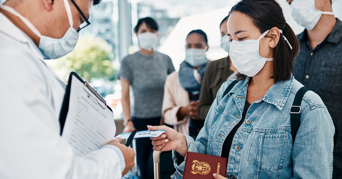 Masked travelers going through airport customs check with passports.