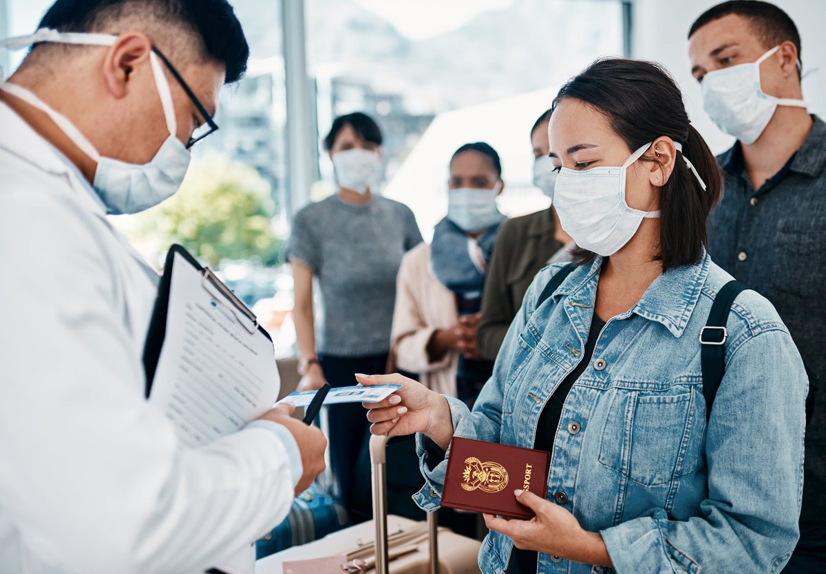 Masked travelers going through airport customs check with passports.