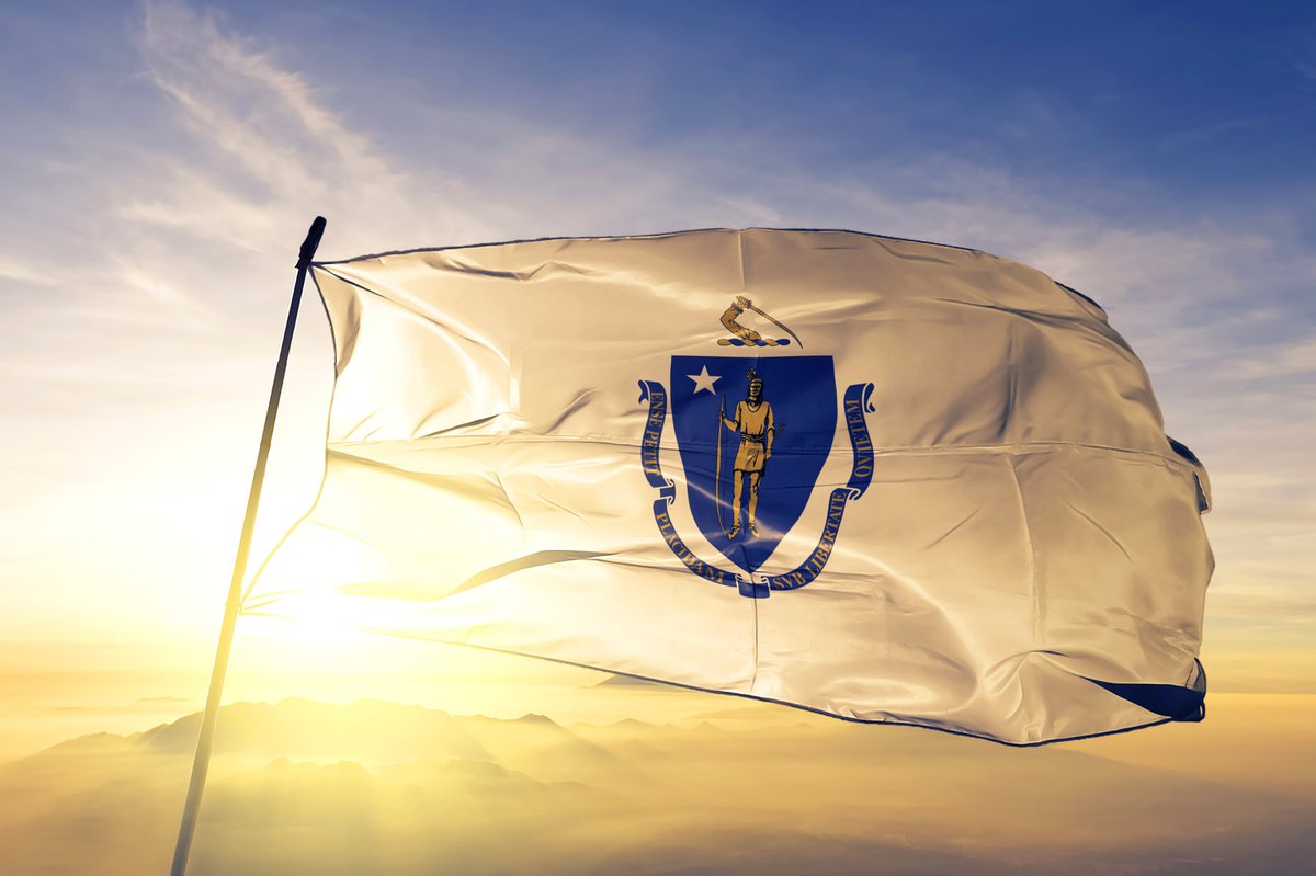 The Massachusetts state flag flying in front of a sunny sky.