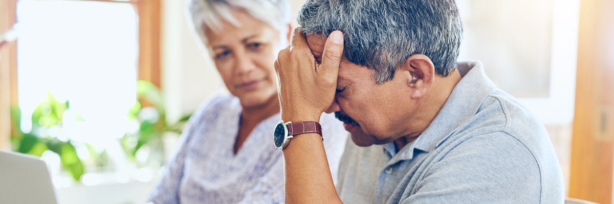 Mature couple appears distraught while looking at laptop.