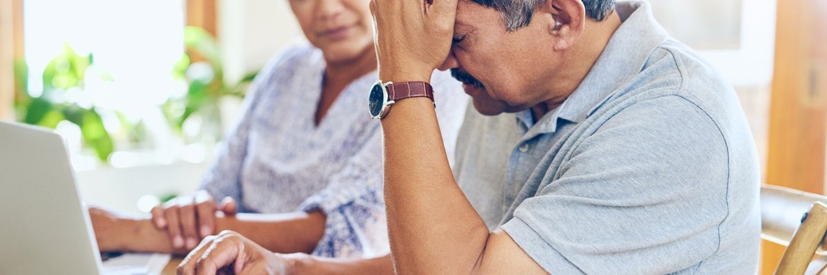 Mature couple appears distraught while looking at laptop.