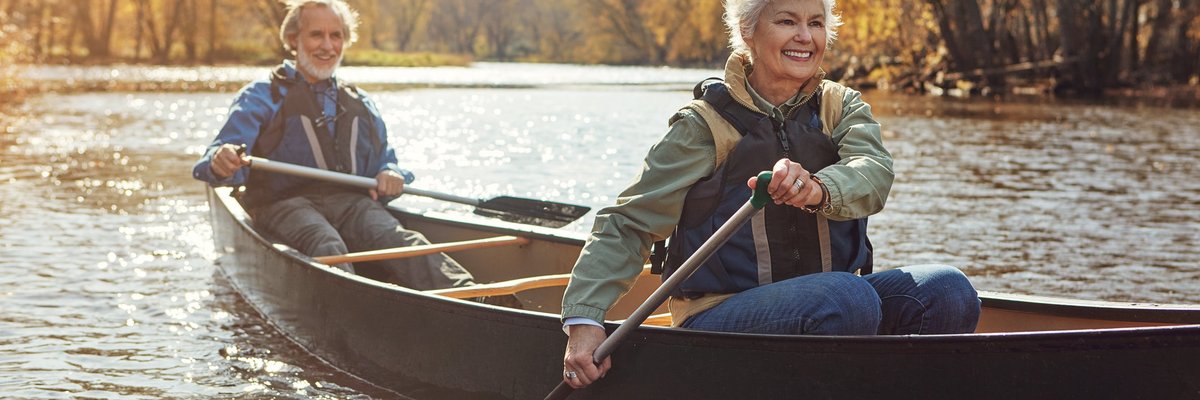 Mature couple rowing together in a canoe.