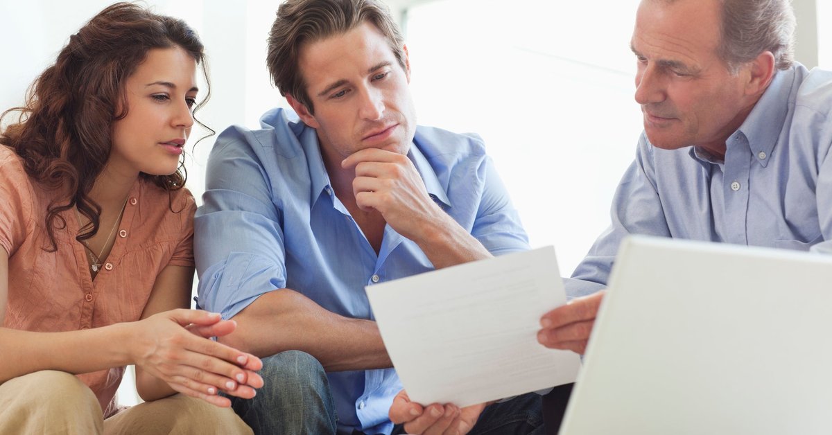 Mature man going over paperwork with young couple.