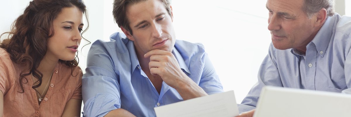 Mature man going over paperwork with young couple.