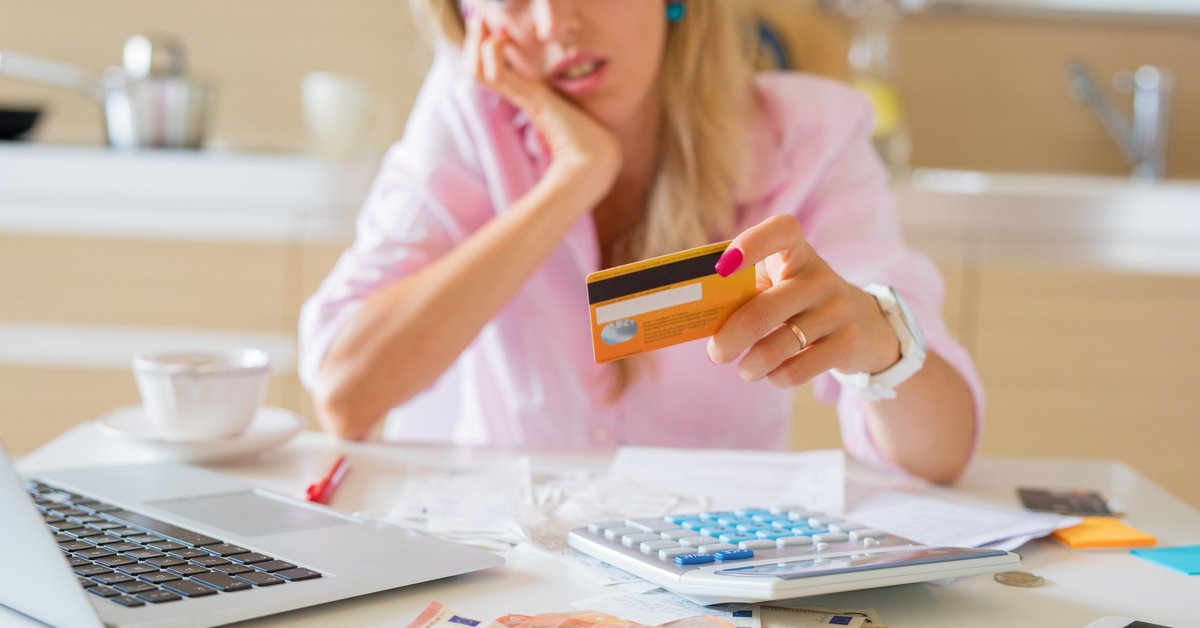 Frustrated Woman Sitting At Table Holding Credit Card