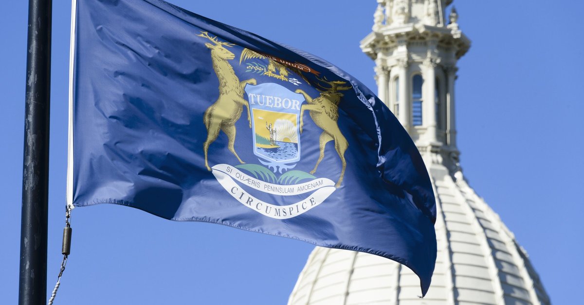 The Michigan state flag fluttering in front of a domed building.