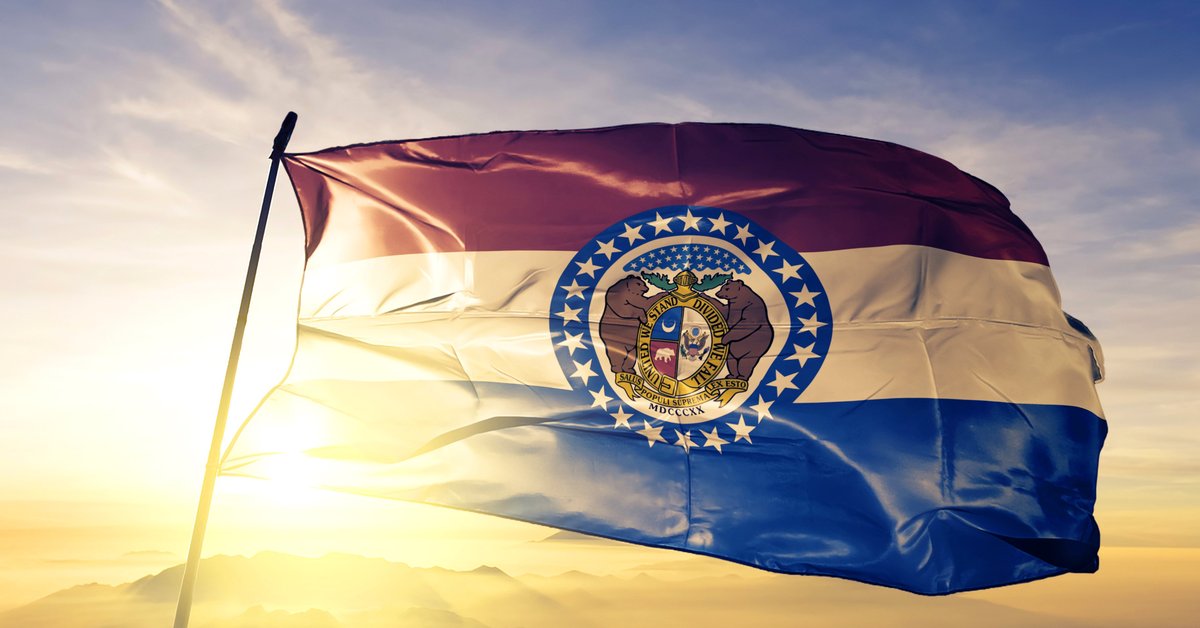 The Missouri state flag in front of a sunny sky.