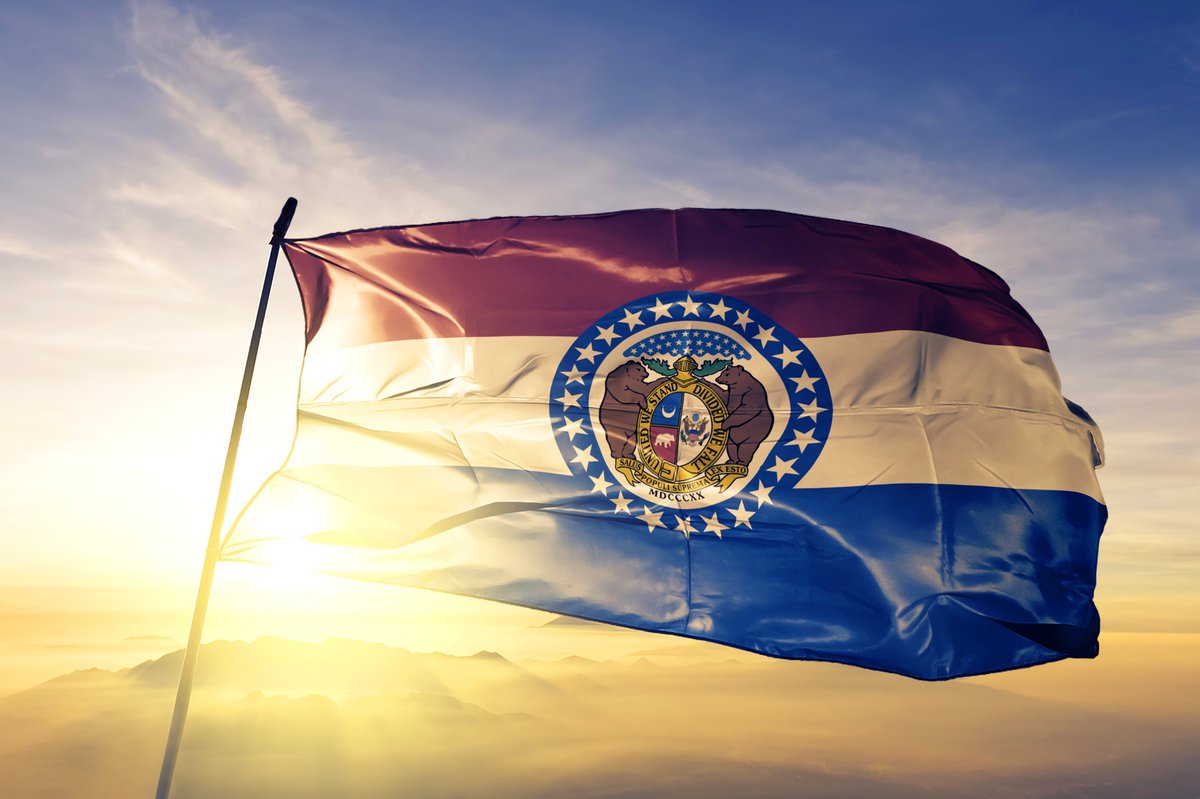 The Missouri state flag in front of a sunny sky.