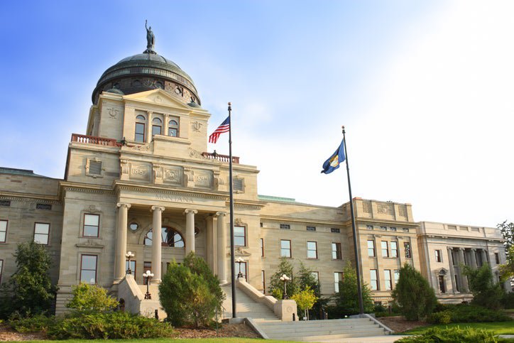 The Montana State Capitol building on a sunny day with flags flying out front.