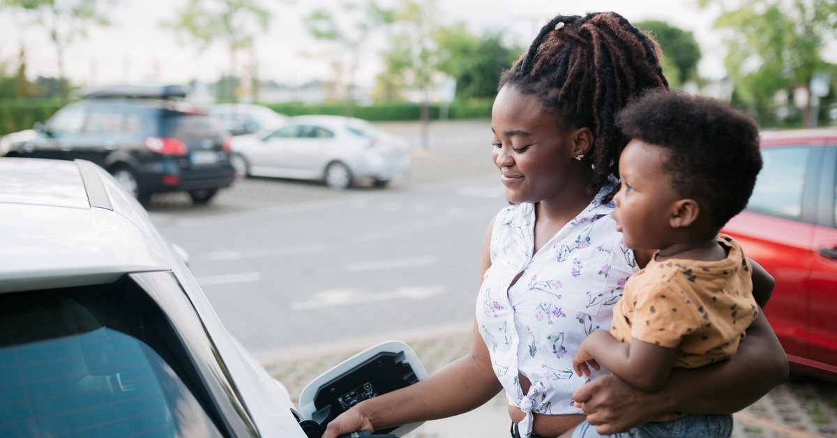 Mother holding her son while charging her electric vehicle