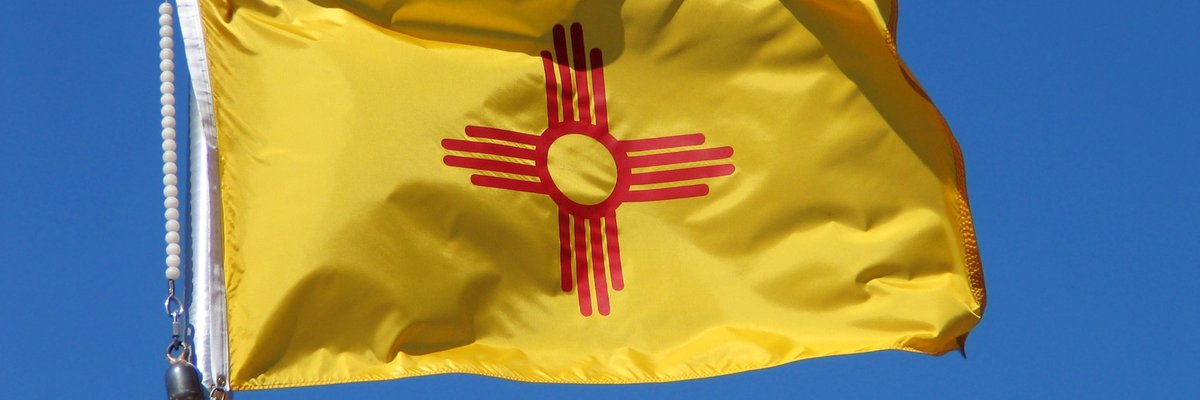 The New Mexico state flag in front of a blue sky.