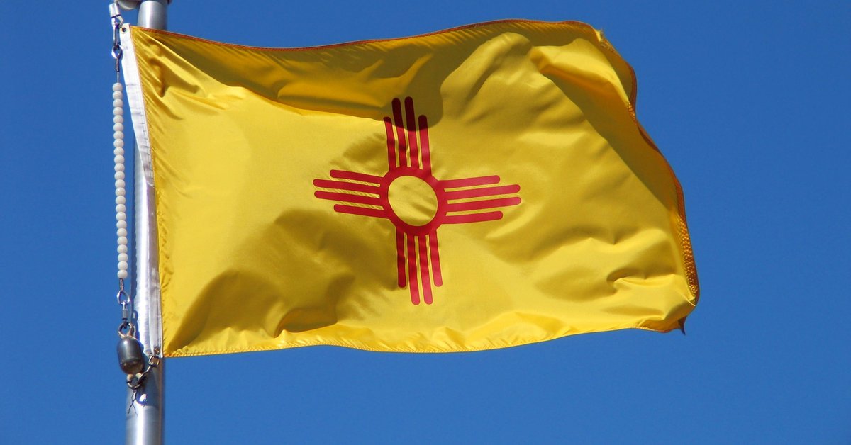 The New Mexico state flag in front of a blue sky.