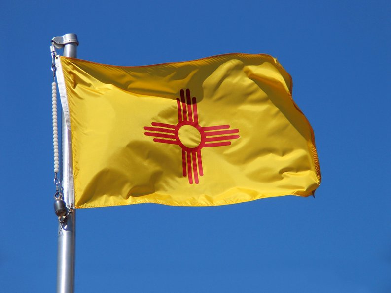The New Mexico state flag in front of a blue sky.