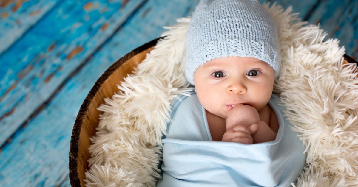 A baby swaddled in a blue blanket and hat.