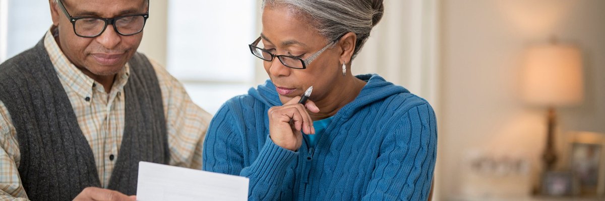 An older couple sit at a table and go over their finances.