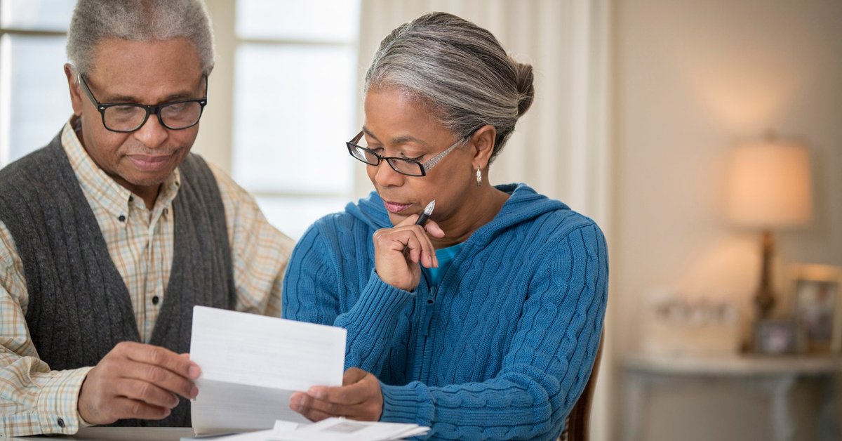 An older couple sit at a table and go over their finances.
