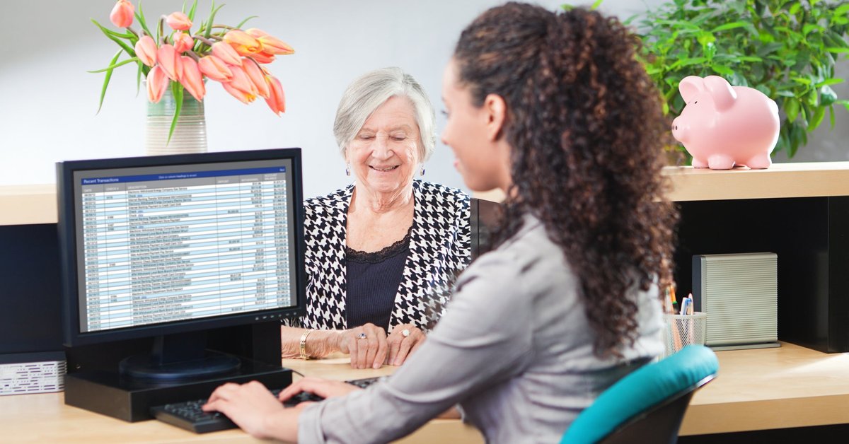 Older woman getting assistance from a bank teller.